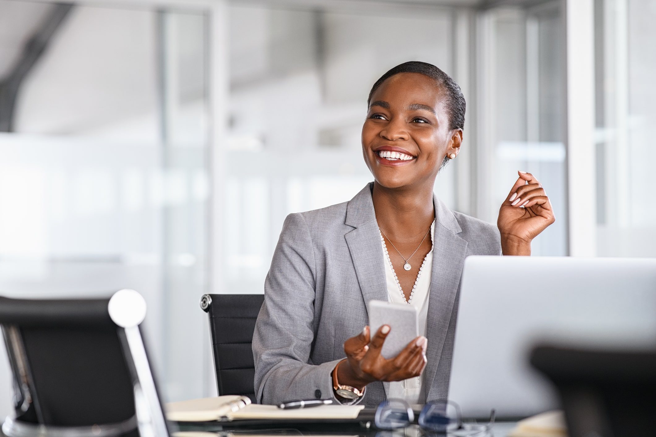 GettyImages-1413763041-min A woman sitting at a table with her cell phone.